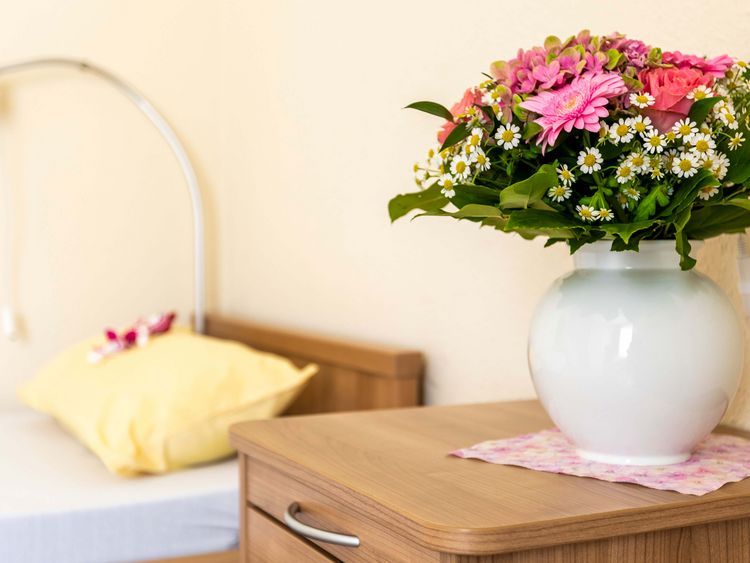 Blumen in einer Vase stehen auf dem Nachttisch im Einzelnzimmer der Seniorenresidenz
