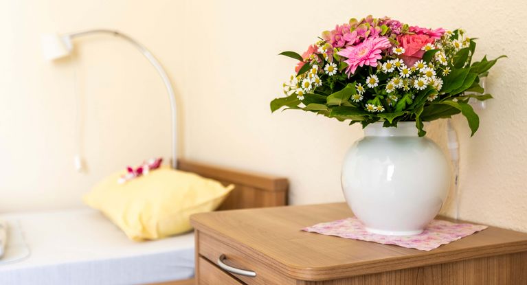 Blumen in einer Vase stehen auf dem Nachttisch im Einzelnzimmer der Seniorenresidenz