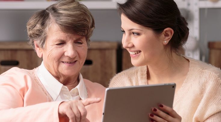 Junge und ältere Frau arbeiten gemeinsam mit einem Tablet