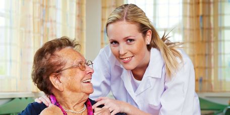 Altenpflegerin legt Seniorin Hände auf die Schulter