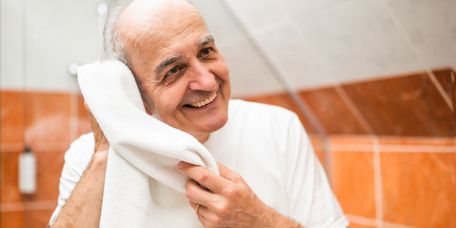 Älterer Mann trockent sich im Bad mit einem Handtuch ab