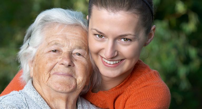 Junge Frau umarmt eine Seniorin