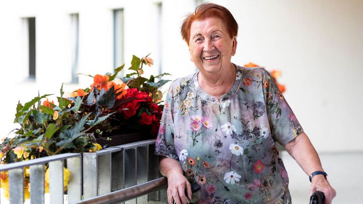 Bewohner steht lachend auf dem Balkon