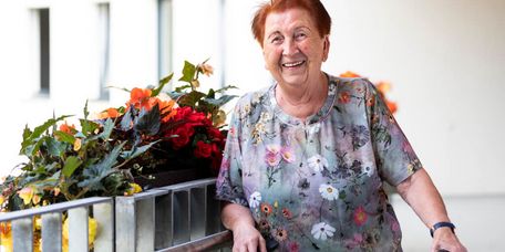 Bewohner steht lachend auf dem Balkon