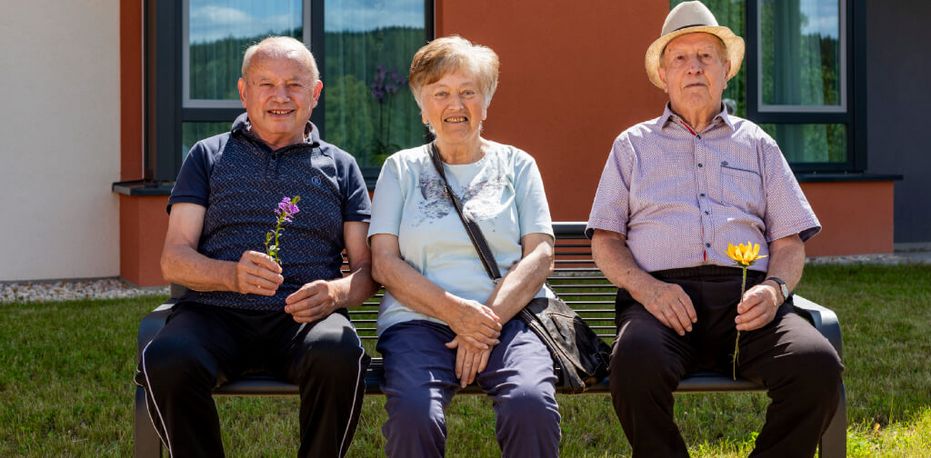 Drei Bewohner genießen die Sonne im Park der Seniorenresidenz