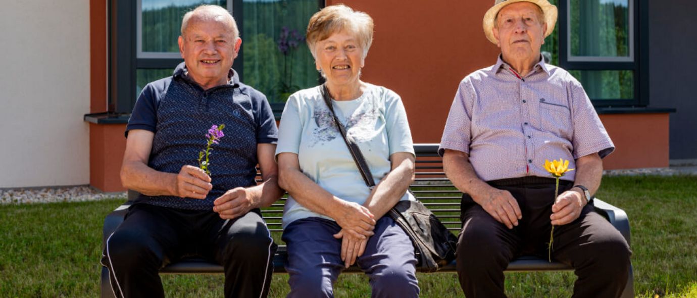 Drei Bewohner genießen die Sonne im Park der Seniorenresidenz