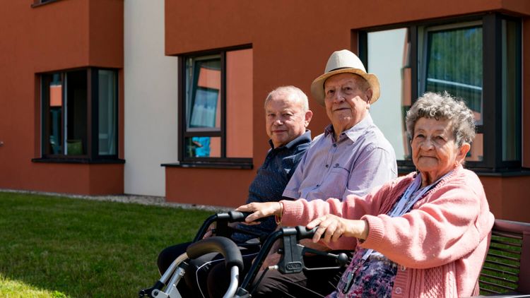 Drei Senioren auf Bank genießen die Sonne 
